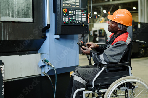 Industrial worker in wheelchair operating complex machinery in manufacturing facility, looking focused and engaged, demonstrating skill and efficiency, emphasizing inclusive work environment photo