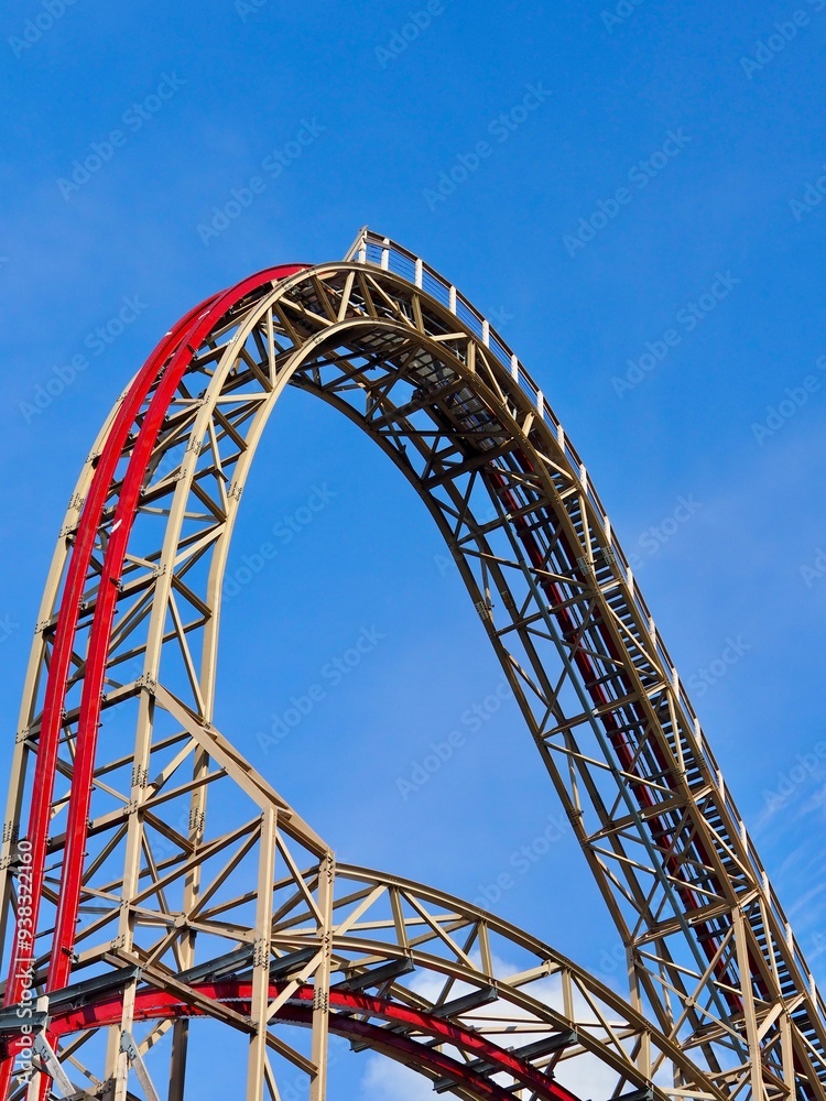 A close-up image of a red rollercoaster track and the blue sky in the background in the amusement park. A close-up image of a red rollercoaster track and the blue sky in the background in the amusement park.