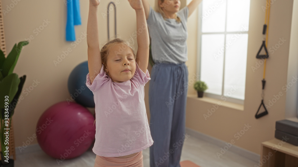 Mother and daughter exercising together indoors at a gymnasium, showcasing a family bonding moment with a woman and child practicing yoga in a sport center Mother and daughter exercising together indoors at a gymnasium, showcasing a family bonding moment with a woman and child practicing yoga in a sport center