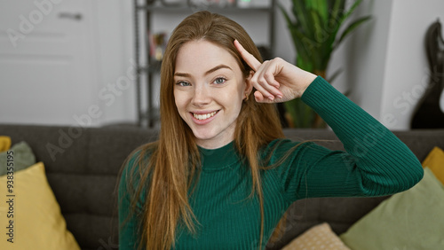 Smiling young woman with blonde hair gesturing at home.