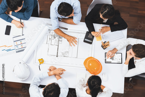 Top view banner of diverse group of civil engineer and client working together on architectural project, reviewing construction plan and building blueprint at meeting table. Prudent