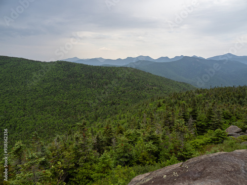 View from the summit of Cascade Mountain, Lake Placid, New York State, with rock in the foreground and surrounding Adirondack forest landscape. photo