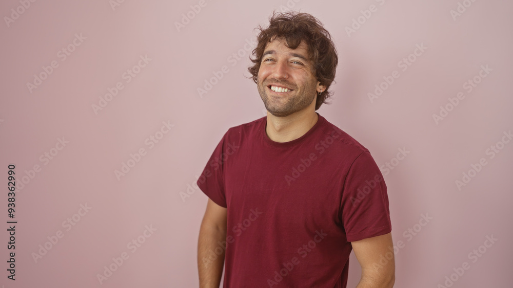 A cheerful young hispanic man with a beard smiling against a soft pink isolated background. A cheerful young hispanic man with a beard smiling against a soft pink isolated background.
