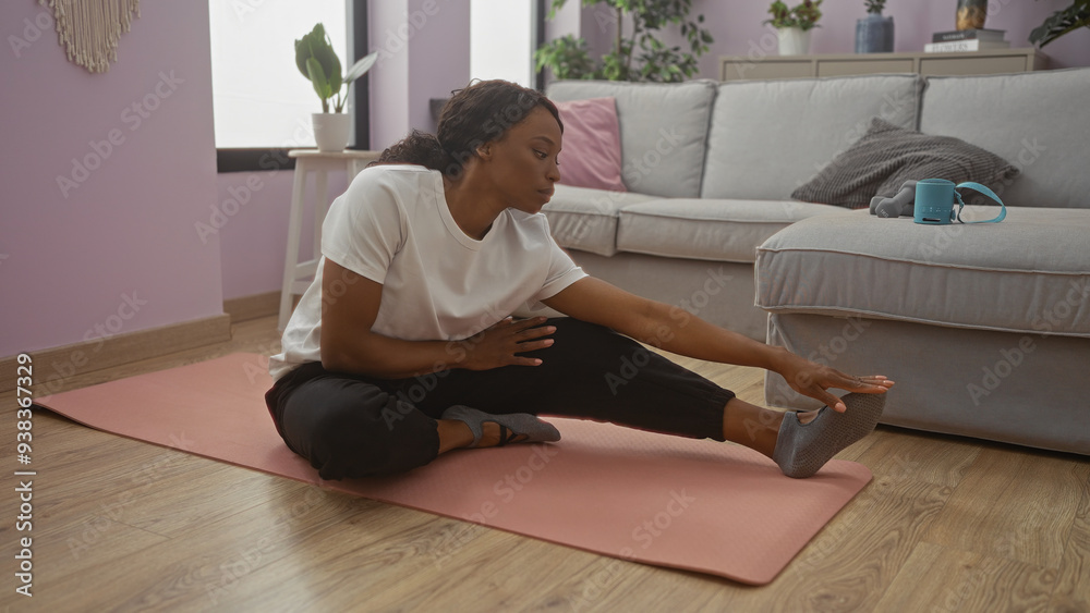 A young african american woman stretches on a yoga mat in her living room, surrounded by cozy decor, embracing fitness and relaxation at home. A young african american woman stretches on a yoga mat in her living room, surrounded by cozy decor, embracing fitness and relaxation at home.