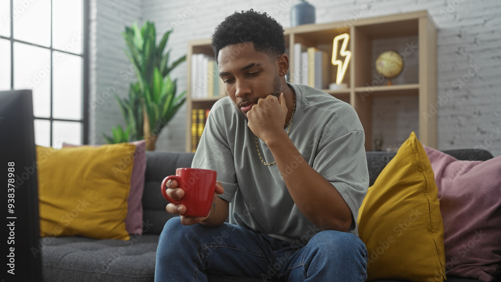 Thoughtful african american man holding mug in modern living room. Thoughtful african american man holding mug in modern living room.