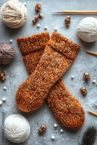 Cozy handmade knit socks with yarn balls and knitting needles on a textured b...