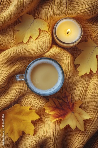 Cozy autumn setup with a warm beverage and candle surrounded by colorful leaves