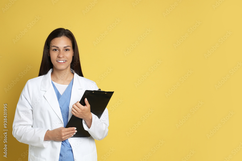Fototapeta premium Portrait of smiling nurse with clipboard on yellow background. Space for text