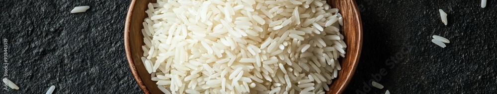 Bowl of uncooked white rice on dark stone surface with natural lighting Bowl of uncooked white rice on dark stone surface with natural lighting
