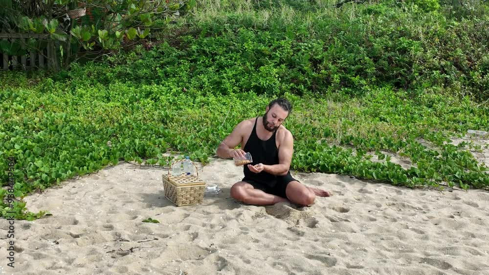 Man on a sunny day at the beach having a picnic, eating and drinking water. Outdoor concept. Aerial view.