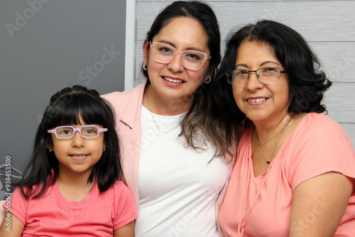 Brunette Latina grandmother, mom and daughter with glasses show their love and support to celebrate Mother's Day