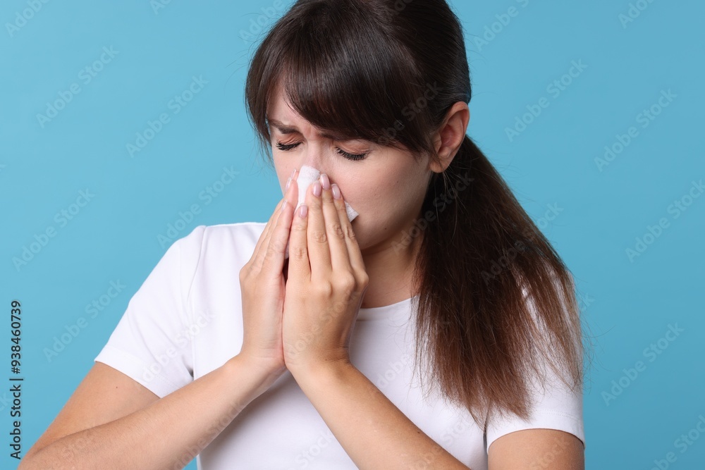 Woman with napkin suffering from sinusitis on light blue background Woman with napkin suffering from sinusitis on light blue background