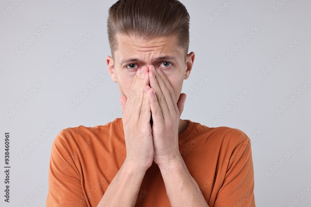 Young man suffering from sinusitis on light grey background Young man suffering from sinusitis on light grey background