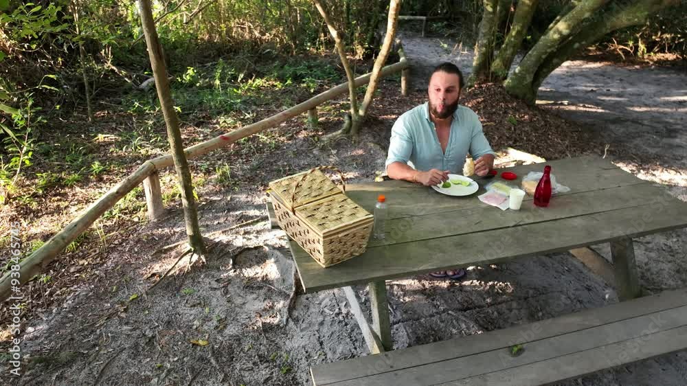 Man eating and handling food during picnic in the woods. Man eating and handling food during picnic in the woods.