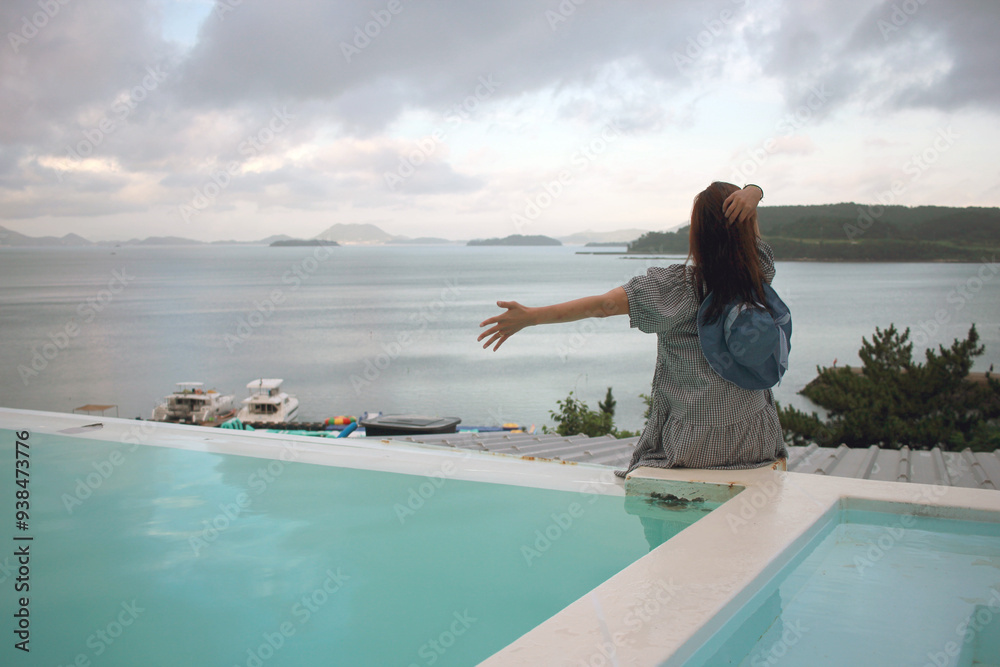 Young woman watching sunrise at a resort with a swimming pool overlooking the sea in Yeosu Young woman watching sunrise at a resort with a swimming pool overlooking the sea in Yeosu