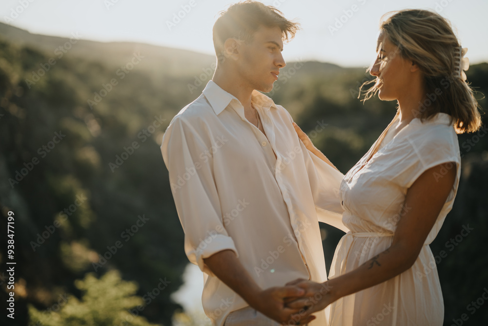 Obraz premium Young couple in love holding hands and sharing a romantic moment in nature at sunset. Warm and tender emotions in a scenic outdoor setting.
