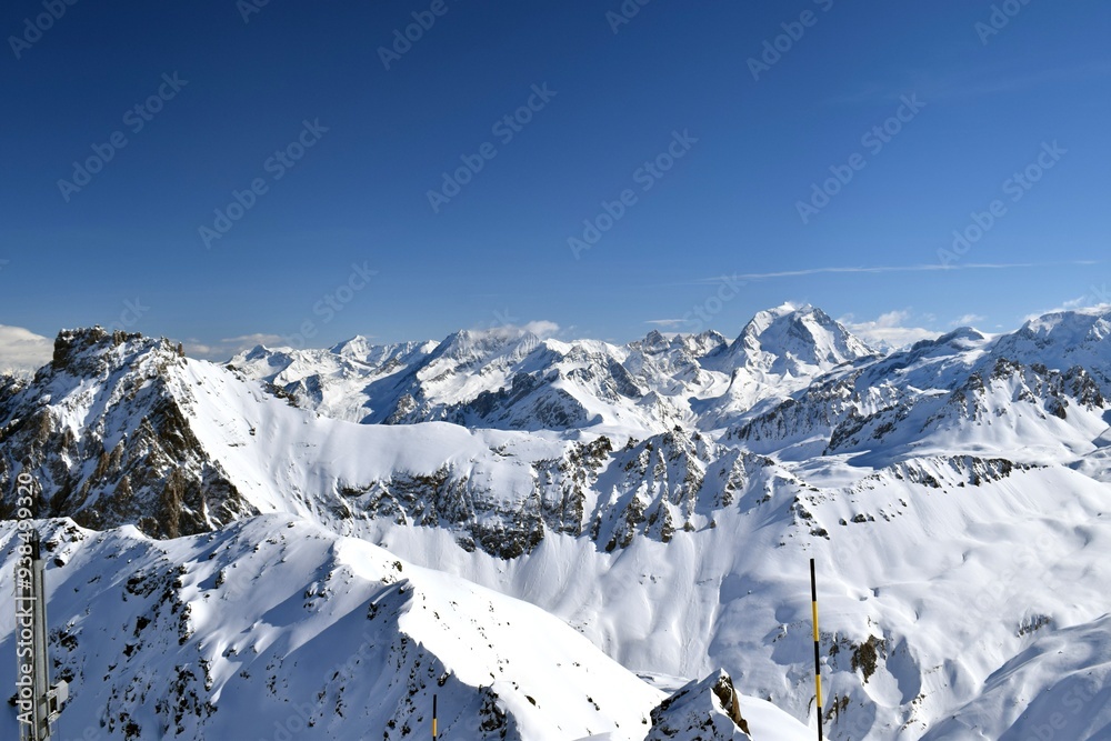 Naklejka premium Snowcapped Alpine mountain peaks in the Three Valleys, France. Breathtaking view from popular Courchevel ski resort located in French Tarentaise Valley.