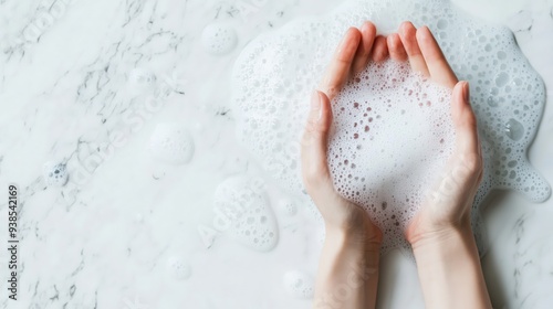 Top view of female hands washing with soap, surrounded by bubble foam on a white background, highlighting hygiene, cleanliness, and self-care.