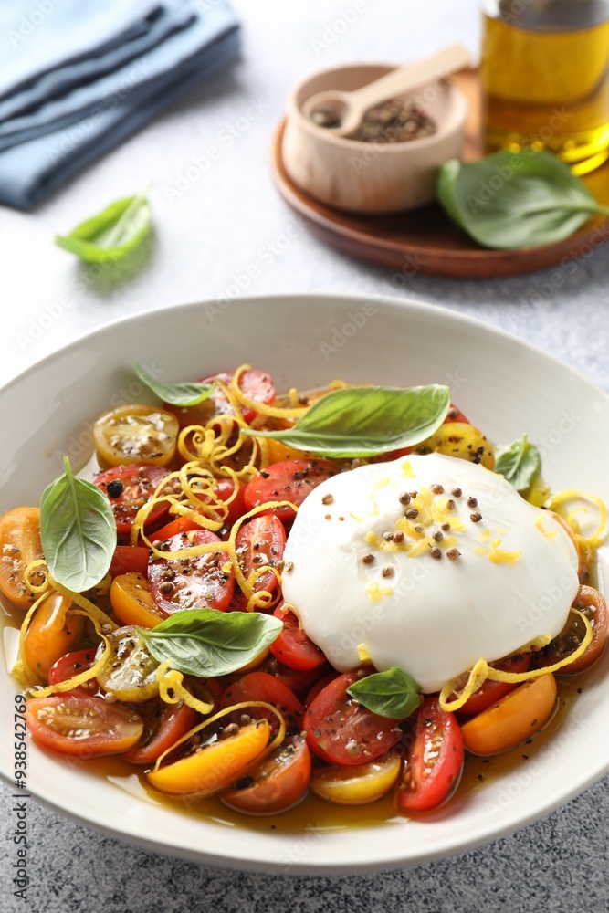 Delicious fresh burrata salad in bowl on light gray table, closeup