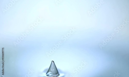 Water Drop Crown: A single water droplet forms a perfect crown shape as it collides with a pool of water, frozen in time against a serene blue backdrop. 