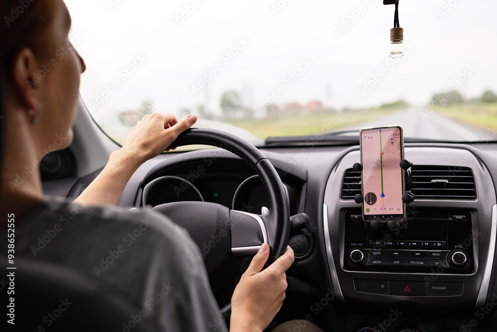 Rear view of a young traveler using a navigator on a mobile phone behind the wheel of a modern car . Rear view of a young traveler using a navigator on a mobile phone behind the wheel of a modern car .