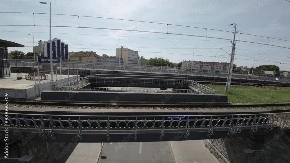 A first-person perspective video of a train station. The video begins with a view of the tracks and the station platform. The camera then pans to the right, showing a waiting area with a bench and a A first-person perspective video of a train station. The video begins with a view of the tracks and the station platform. The camera then pans to the right, showing a waiting area with a bench and a