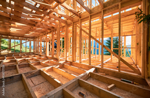 Under-construction residential wooden frame home located near a forest. Commencement of a new construction project for a cozy house or a mountain cottage. Idea of contemporary ecological construction.