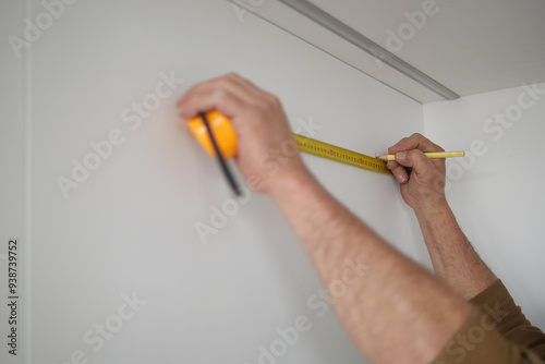 Man measuring wall with a tape measure 
