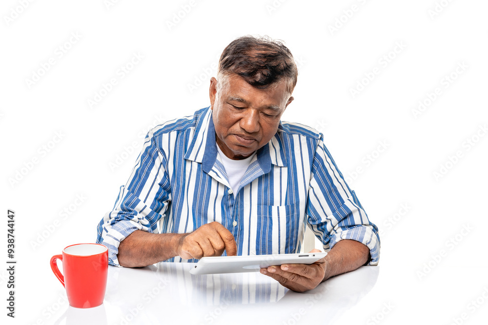 Elderly Asian man using tablet computer and drinking coffee isolated on white background. Elderly Asian man using tablet computer and drinking coffee isolated on white background.