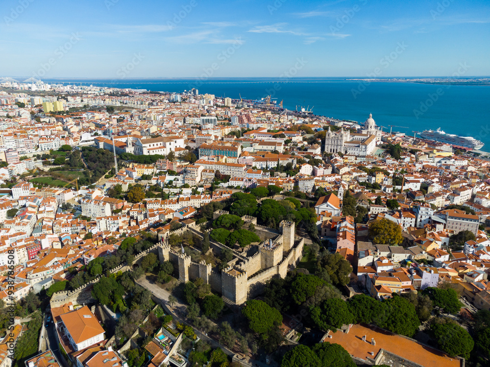 Lisbon, Portugal: Aerial drone view of the Lisbon medieval castle in the old town in Portugal capital city with the Tages river in the background Lisbon, Portugal: Aerial drone view of the Lisbon medieval castle in the old town in Portugal capital city with the Tages river in the background