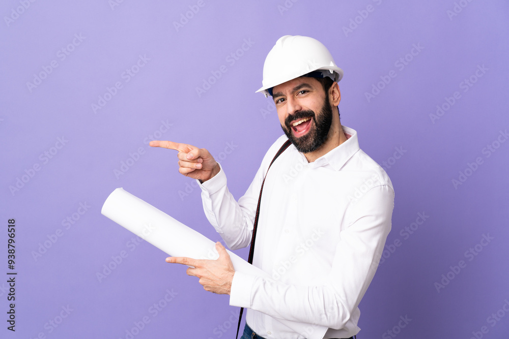 Young architect man with helmet and holding blueprints over isolated purple background pointing finger to the side and presenting a product Young architect man with helmet and holding blueprints over isolated purple background pointing finger to the side and presenting a product