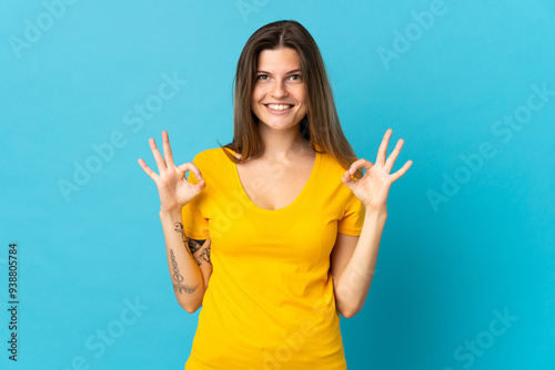 Young slovak woman isolated on blue background showing ok sign with two hands