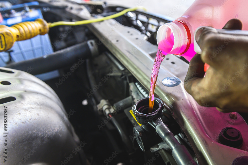 Auto mechanic pouring antifreeze engine coolant into car radiator fill ...