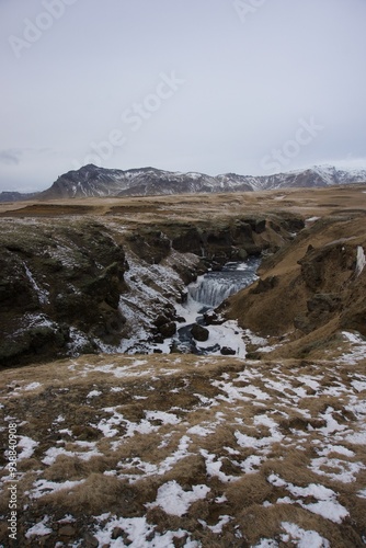 River with snow in Iceland, with a mountain in background.