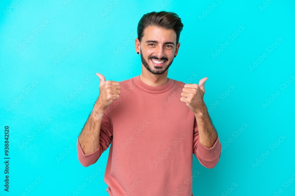 Young caucasian man isolated on blue background with thumbs up gesture and smiling