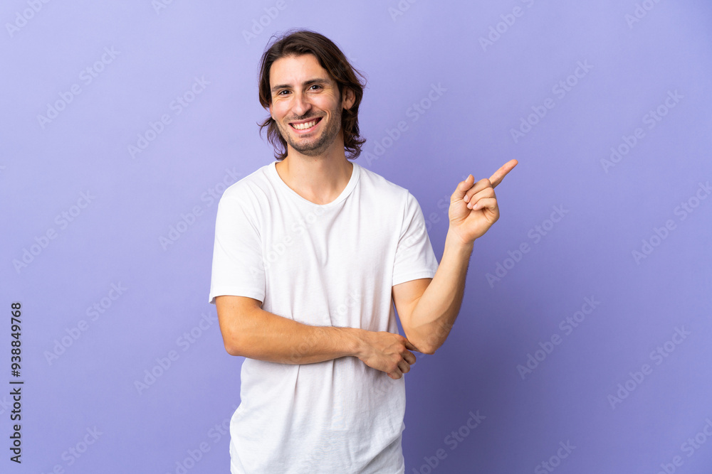 Young handsome man isolated on purple background happy and pointing up Young handsome man isolated on purple background happy and pointing up