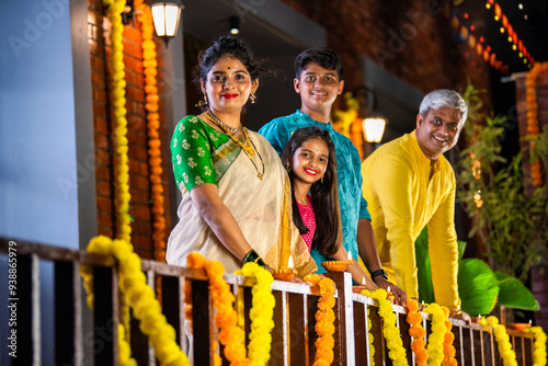 Family of four arranging clay diyas for Diwali, brightening their home with festive ligh photo