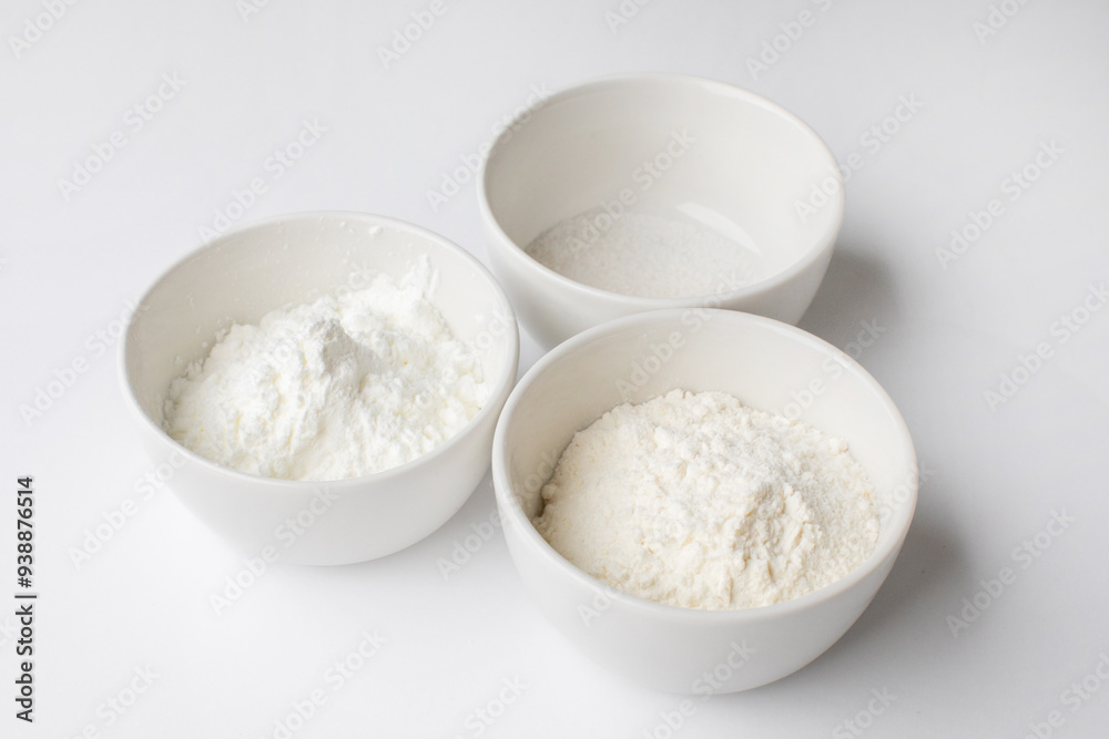 Three white bowls filled with various baking powders on a white background, symbolizing essential ingredients for holiday baking Three white bowls filled with various baking powders on a white background, symbolizing essential ingredients for holiday baking