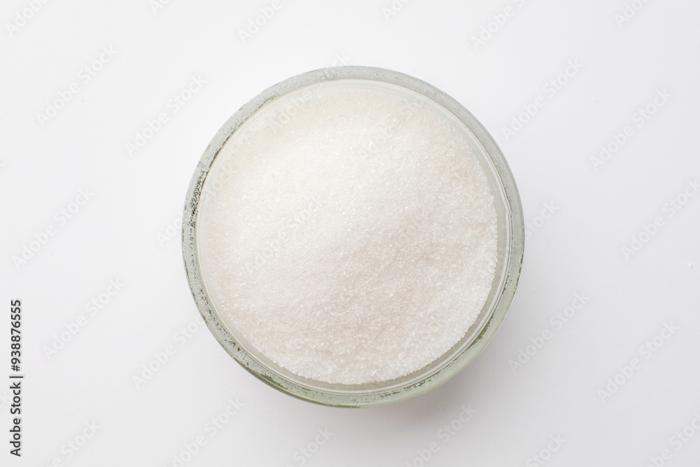 A close-up of a glass bowl filled with white sugar, highlighting the concept of unhealthy dietary habits and obesity A close-up of a glass bowl filled with white sugar, highlighting the concept of unhealthy dietary habits and obesity
