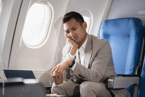 Stress businessman is sitting in the airplane, under stress from working.