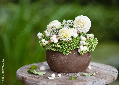 Autumn flower arrangement with white dahlia, showy stonecrop flowers and snowberry branches in a rustic vase. Floristic or gardening concept. Selective focus. Copy space. photo