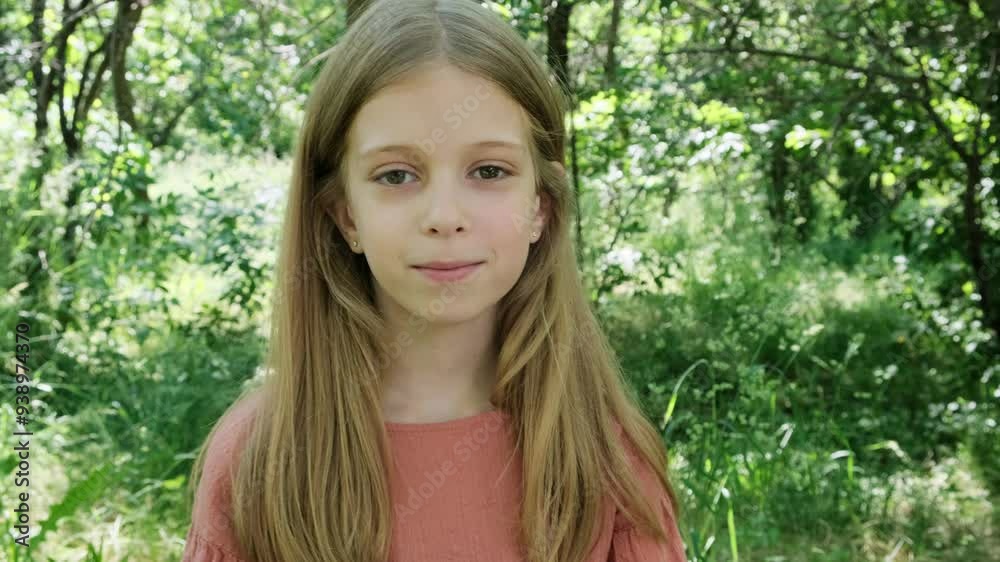 The girl in the forest smiles and tucks her hair behind her ear. The girl in the forest smiles and tucks her hair behind her ear.