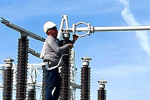 Construction of Substation: 115 kV aluminium tube busbar installation in the switchyard by an electrical worker.