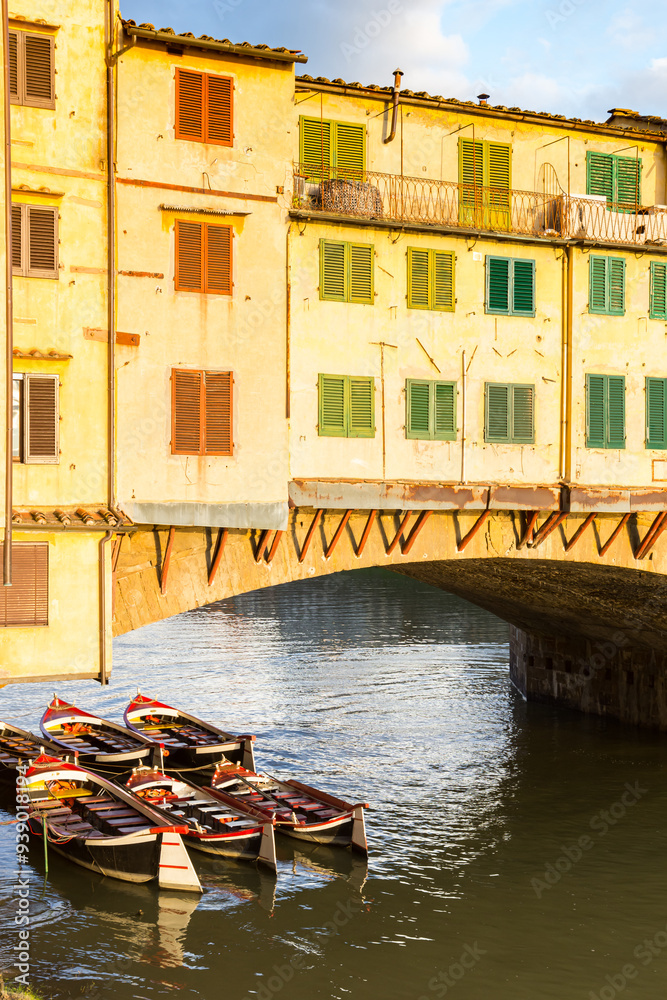 Small wooden rowboats under the Ponte Vecchio bridge in Florence, Italy