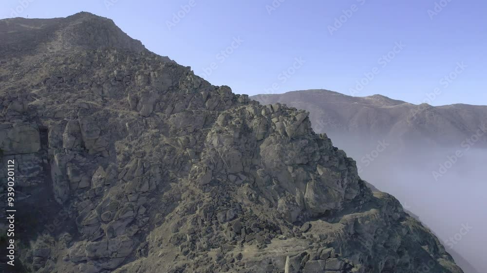 Clouds gradually disperse to reveal the peak of a mountain