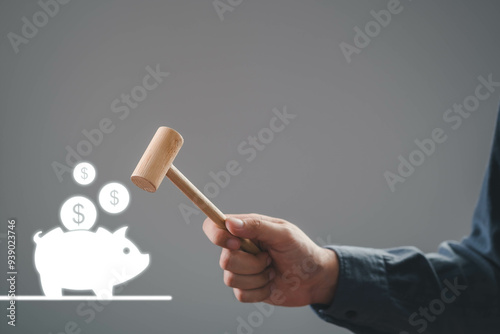 A hand holding a gavel above a piggy bank, symbolizing finance, savings, and investment decisions. photo
