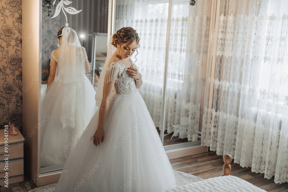 A bride is getting ready for her wedding, standing in front of a mirror. The image has a dreamy, romantic mood, as the bride is dressed in a beautiful white gown and is surrounded by a soft A bride is getting ready for her wedding, standing in front of a mirror. The image has a dreamy, romantic mood, as the bride is dressed in a beautiful white gown and is surrounded by a soft