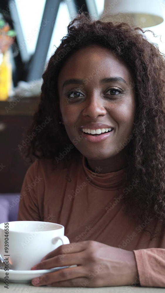 A very beautiful African American woman is sitting at a cafe table with a cup of coffee or tea. A very beautiful African American woman is sitting at a cafe table with a cup of coffee or tea.