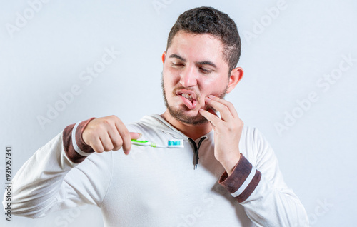 Guy with gum pain holding toothbrush. Suffering man with gingivitis holding toothbrush isolated