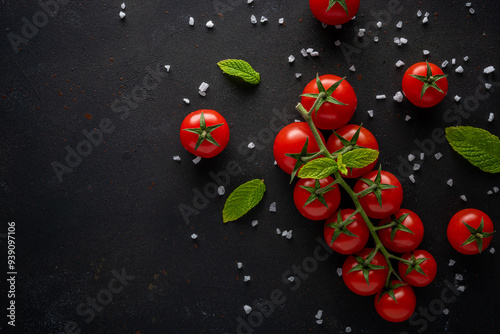 Fresh cherry tomatoes on a black background with spices. Food background. Top view.